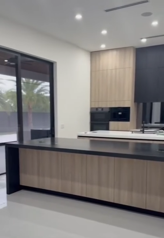 Modern kitchen featuring a large wood-based island with a black waterfall counter and matching two-tone cabinetry.