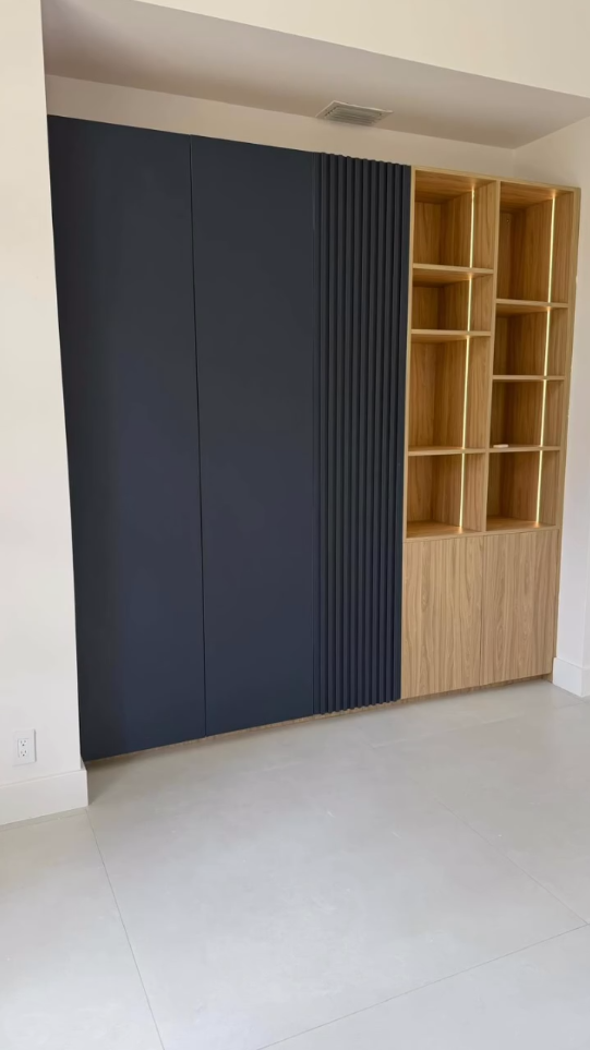 Custom modern built-in cabinet with navy blue doors, fluted accent panels, and illuminated light wood open shelving