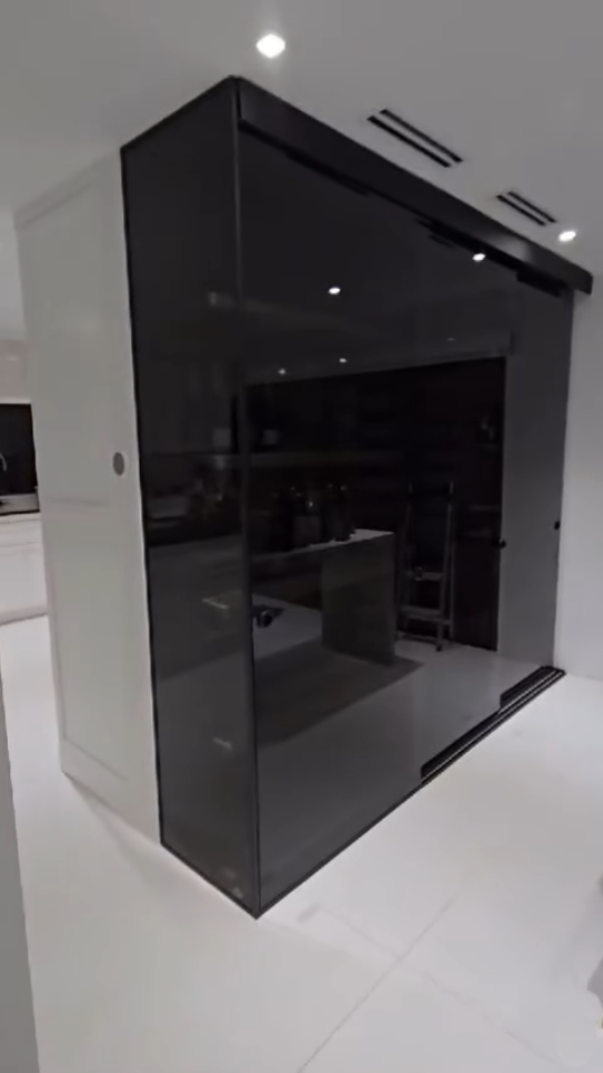 Luxury glass-enclosed liquor cabinet with integrated LED lighting and minimalist black framing.