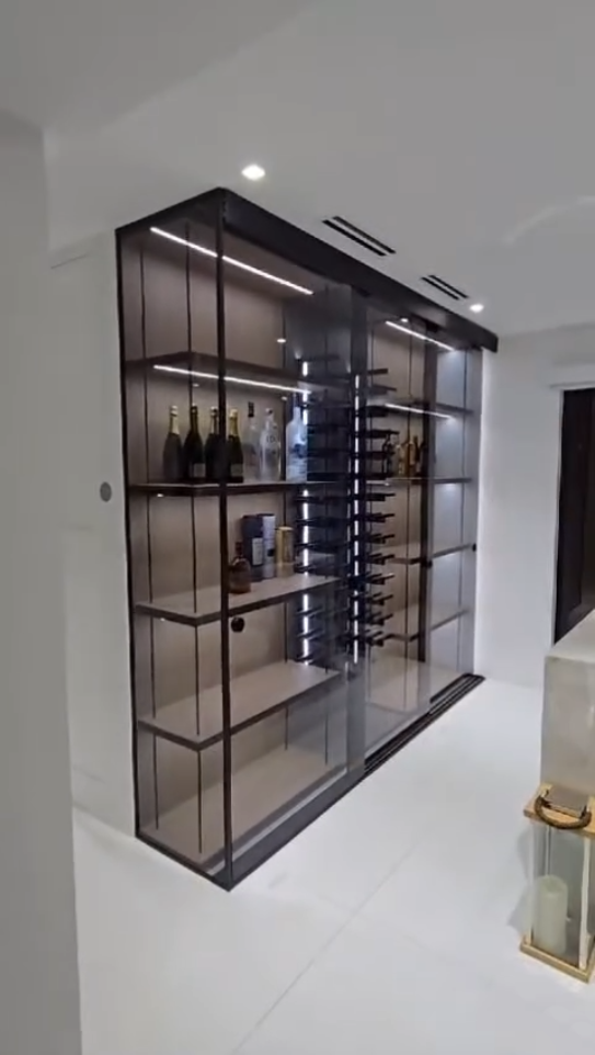 Luxury glass-enclosed liquor cabinet with integrated LED lighting and minimalist black framing.