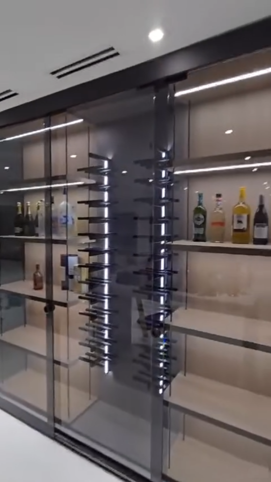 Luxury glass-enclosed liquor cabinet with integrated LED lighting and minimalist black framing.