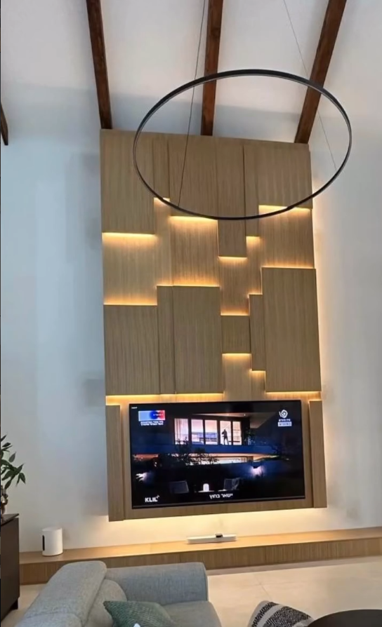 Minimalist living room design with wall-mounted television, oak floating paneling, and neutral color palette.