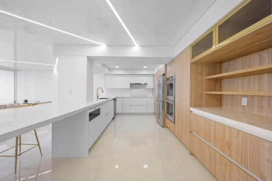 Luxury minimalist kitchen, architectural linear lighting, and integrated wood cabinets.