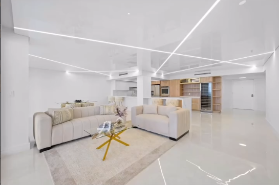 Luxury living room design with architectural LED ceiling lighting, white stretch ceiling, and modern open-plan layout.