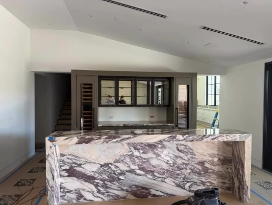 Luxury kitchen featuring a purple and white marble waterfall island and custom built-in bar.
