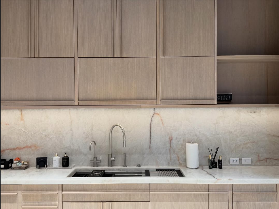 Modern kitchen workstation with luxury marble backsplash, integrated black sink, designer faucets, and custom wood cabinetry design.