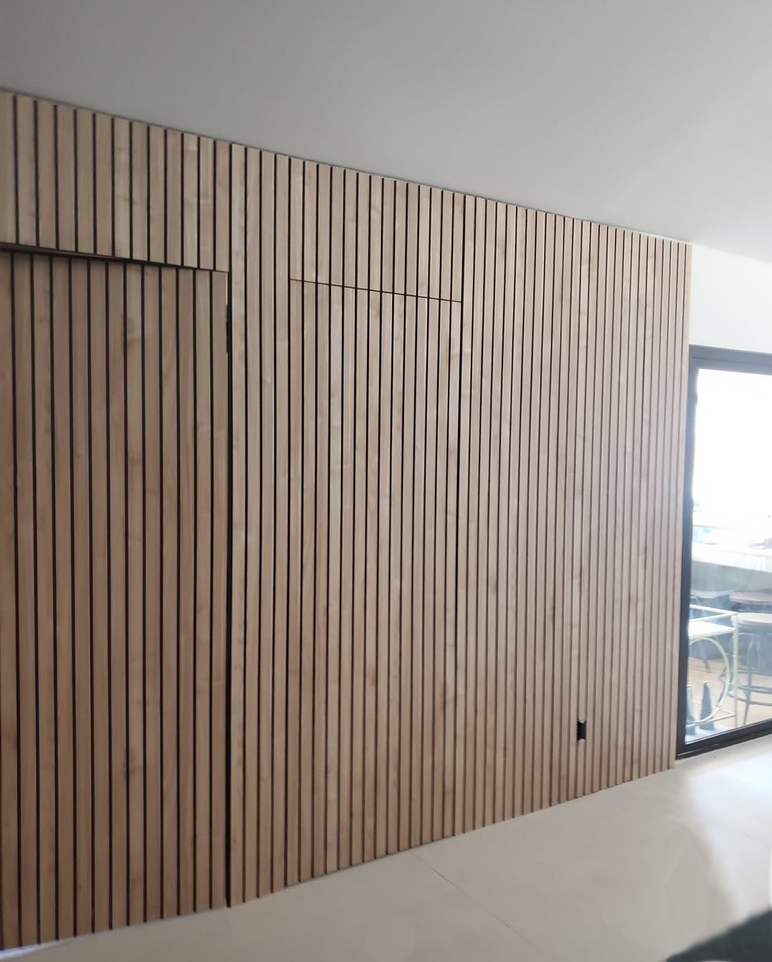 Modern light wood fluted wall paneling featuring a seamless hidden door and vertical slat texture.