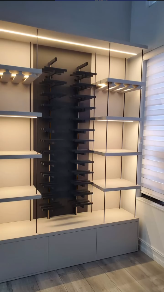 Custom illuminated display shelving unit with integrated wine rack and minimalist grey cabinetry.