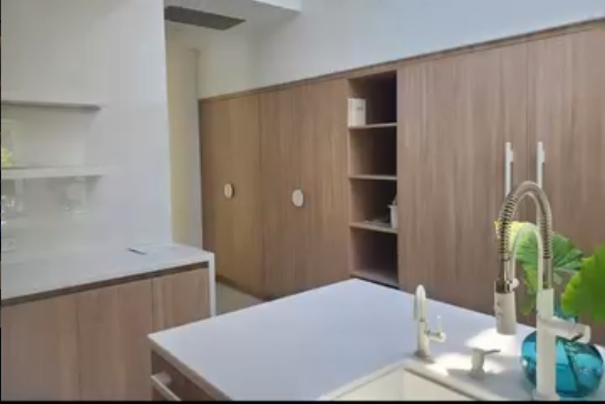 Minimalist kitchen design featuring custom wood cabinetry, a white countertop, and modern white hardware.